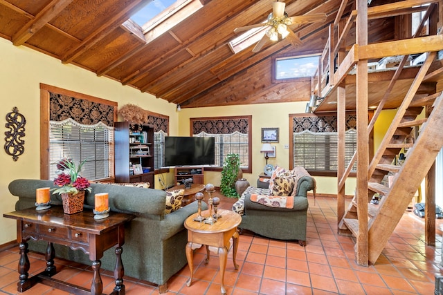 tiled living room featuring vaulted ceiling with skylight, wood ceiling, stairway, a ceiling fan, and baseboards