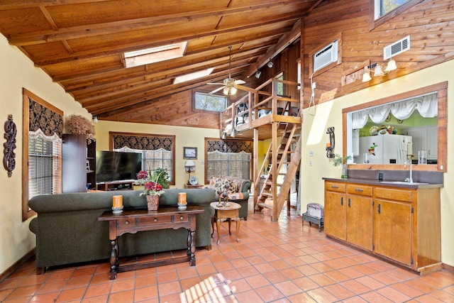 living area featuring ceiling fan, a skylight, wood ceiling, and light tile patterned floors