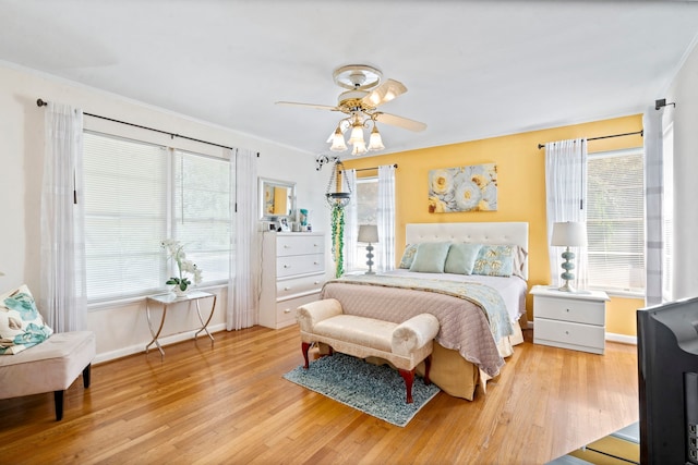 bedroom featuring baseboards, wood finished floors, multiple windows, and a ceiling fan