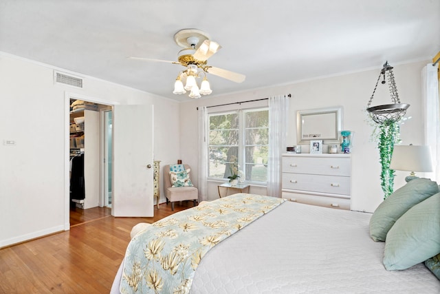 bedroom with crown molding, baseboards, visible vents, ceiling fan, and wood finished floors
