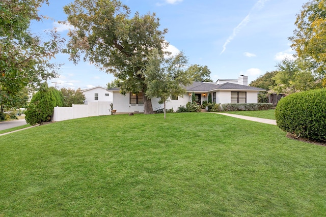 ranch-style house with a chimney, fence, and a front lawn