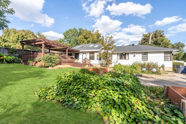 rear view of house with a lawn, fence, a wooden deck, and a pergola