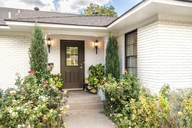 property entrance featuring brick siding and roof with shingles