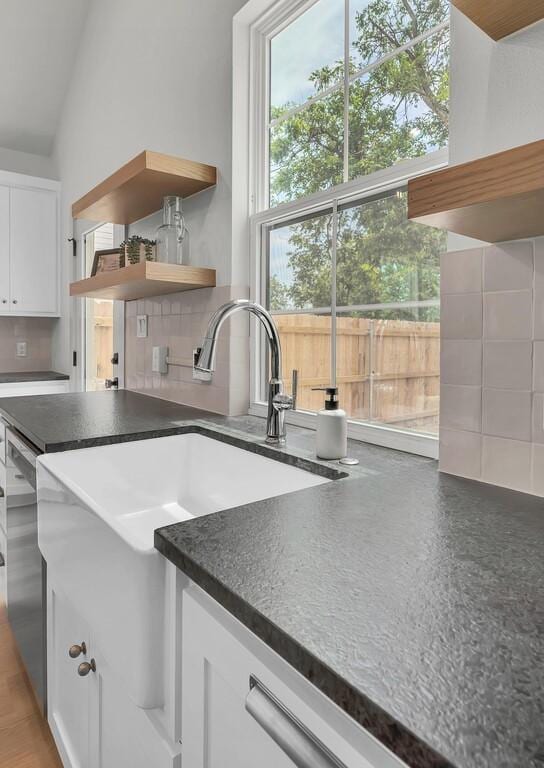 538 Proctor Ave, Waco, TX 76708 - kitchen with dark countertops, backsplash, open shelves, white cabinets, and a sink