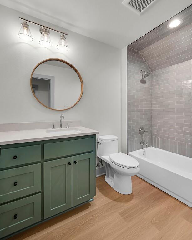 538 Proctor Ave, Waco, TX 76708 - bathroom featuring toilet, wood finished floors, vanity, and shower / bathtub combination