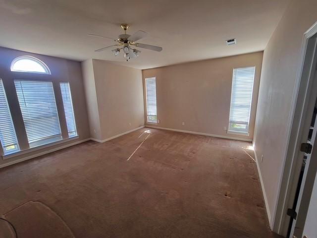 empty room with baseboards, a wealth of natural light, visible vents, and a ceiling fan