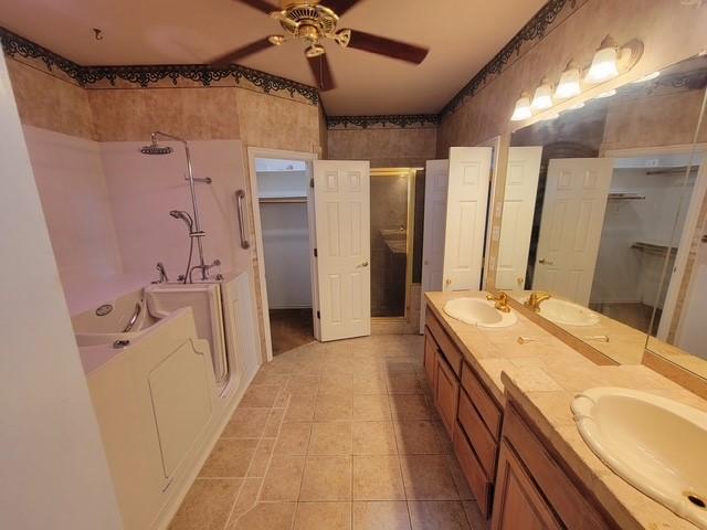 bathroom featuring a shower stall, double vanity, a ceiling fan, a sink, and tile patterned flooring