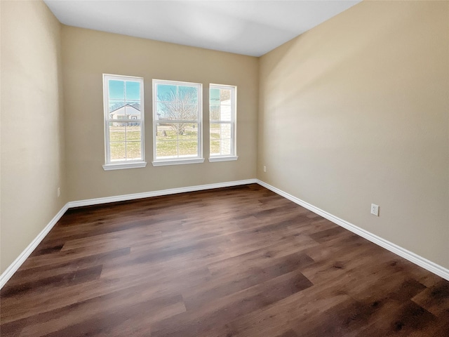 unfurnished room featuring baseboards and dark wood-style flooring