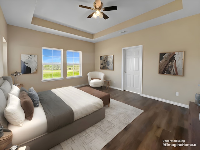 bedroom featuring a tray ceiling, baseboards, visible vents, and wood finished floors