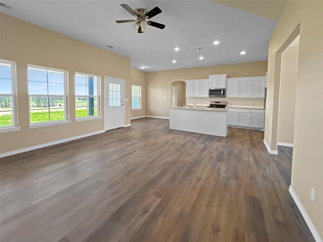 kitchen featuring open floor plan, white cabinetry, baseboards, ceiling fan, and appliances with stainless steel finishes