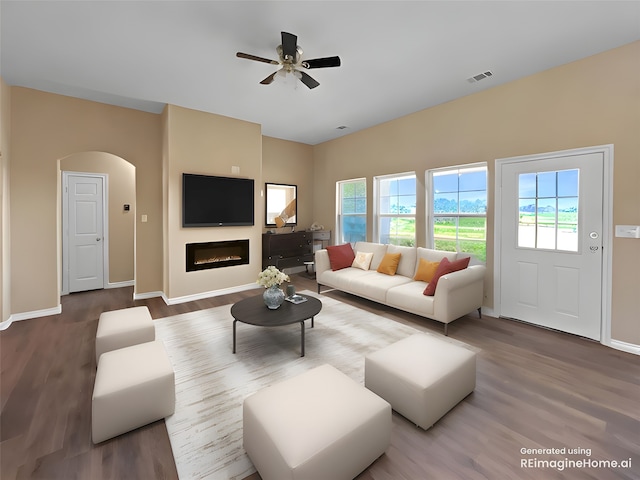 living room with visible vents, ceiling fan, wood finished floors, arched walkways, and a glass covered fireplace