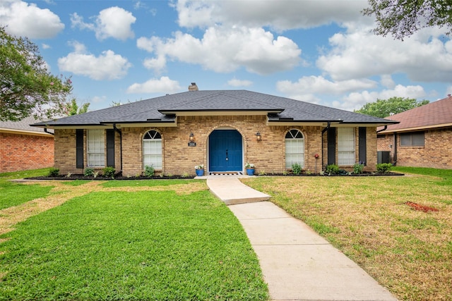 view of front of property with roof with shingles, a front yard, brick siding, central AC, and a chimney