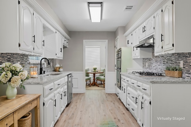 1206 Mayapple Dr, Garland, TX 75043 - kitchen with under cabinet range hood, white cabinetry, visible vents, and appliances with stainless steel finishes