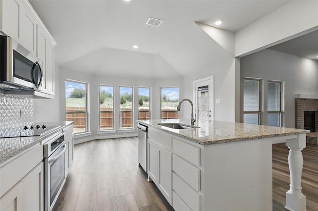 116 Mesa Dr, Glen Rose, TX 76043 - kitchen with a sink, appliances with stainless steel finishes, wood finished floors, white cabinetry, and an island with sink