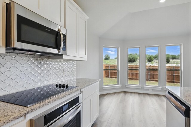 116 Mesa Dr, Glen Rose, TX 76043 - kitchen featuring appliances with stainless steel finishes, decorative backsplash, light stone counters, white cabinetry, and vaulted ceiling