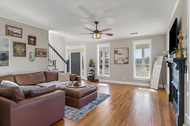 living area featuring visible vents, a ceiling fan, stairway, and hardwood / wood-style floors
