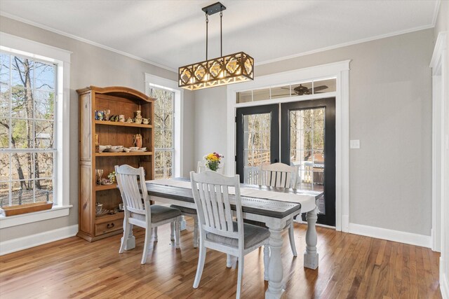 dining room with baseboards, crown molding, light wood-style floors, and a chandelier