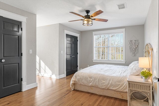 bedroom featuring ceiling fan, baseboards, light wood finished floors, and visible vents