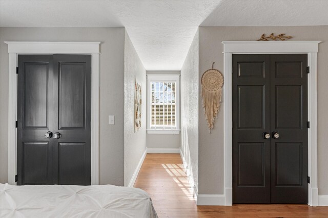 bedroom with a textured wall, baseboards, a textured ceiling, and wood finished floors