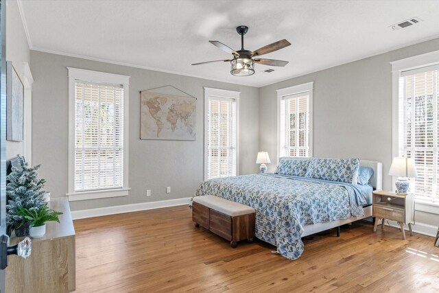 bedroom featuring baseboards, light wood-type flooring, crown molding, and visible vents