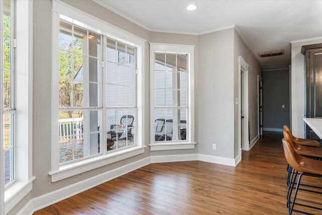 interior space featuring crown molding, wood finished floors, baseboards, visible vents, and recessed lighting