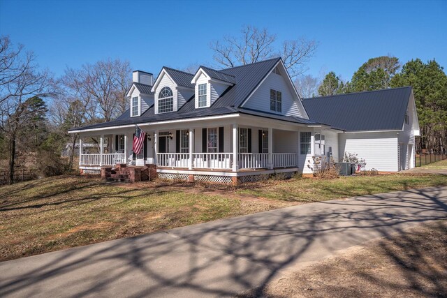 view of front of home with a chimney, a front lawn, metal roof, central AC unit, and a porch