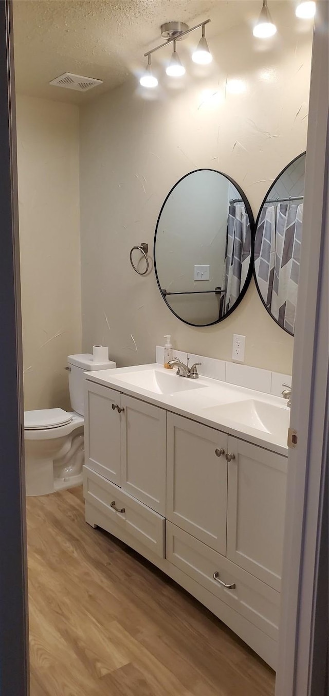 425 Oxford Dr, Sherman, TX 75092 - bathroom with toilet, vanity, wood finished floors, a textured ceiling, and visible vents