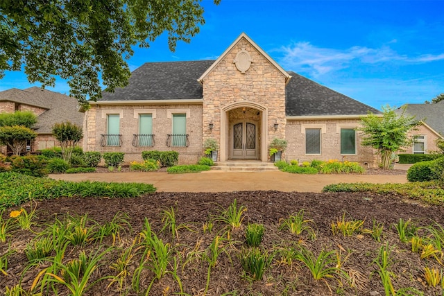 view of front of home featuring stone siding, a shingled roof, french doors, and brick siding