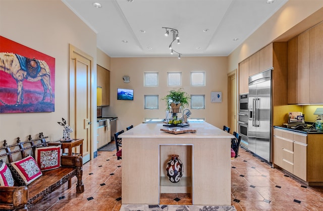 kitchen with a center island, light tile patterned flooring, ornamental molding, and stainless steel appliances