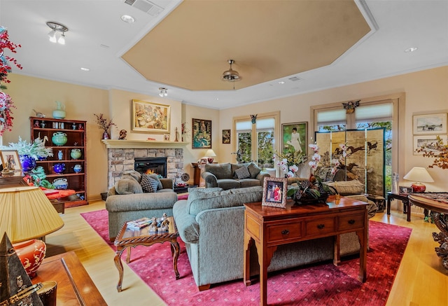 living room with a fireplace, visible vents, ornamental molding, and wood finished floors