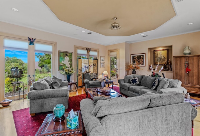 living room with visible vents, crown molding, wood finished floors, a tray ceiling, and french doors