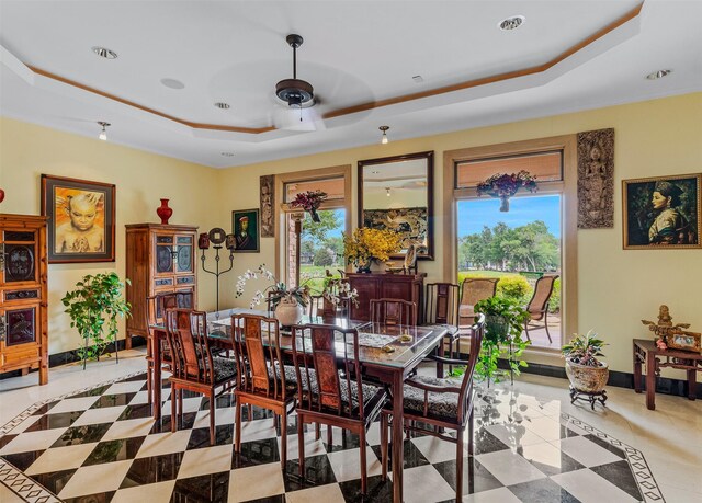 dining space featuring a ceiling fan, a raised ceiling, and baseboards