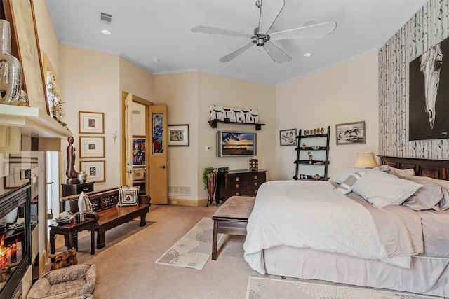 bedroom with visible vents, a glass covered fireplace, crown molding, and light colored carpet