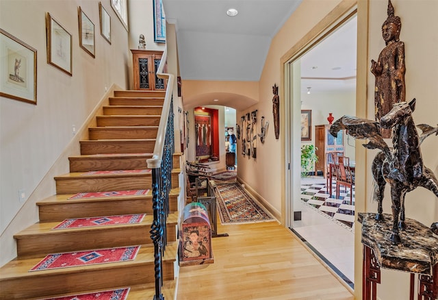 entryway with recessed lighting, arched walkways, stairway, and wood finished floors