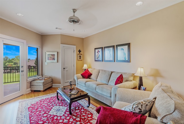 living area with crown molding, baseboards, visible vents, a ceiling fan, and wood finished floors