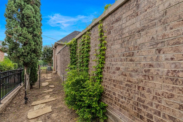 view of side of home featuring brick siding and fence