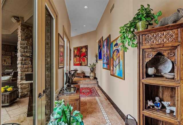 hallway featuring ornamental molding, visible vents, and light tile patterned floors