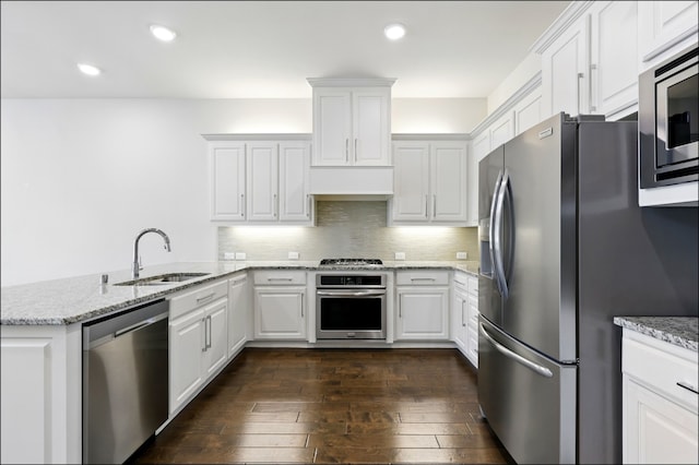 kitchen with stainless steel appliances, white cabinetry, a sink, and a peninsula