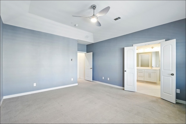 unfurnished bedroom with ceiling fan, light colored carpet, visible vents, baseboards, and ensuite bath