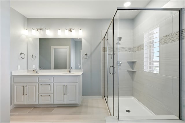 full bath with double vanity, baseboards, a stall shower, and a sink