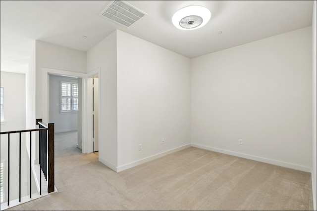 spare room with baseboards, light colored carpet, and visible vents