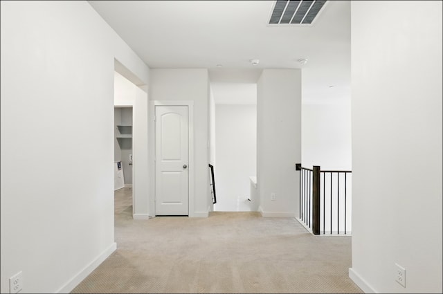 hall featuring visible vents, carpet, baseboards, and an upstairs landing