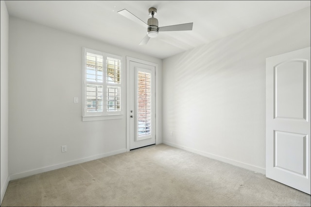 spare room featuring baseboards, a ceiling fan, and light carpet