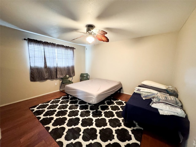 311 S Fir Ave, Munday, TX 76371 - bedroom featuring baseboards, wood finished floors, and a ceiling fan