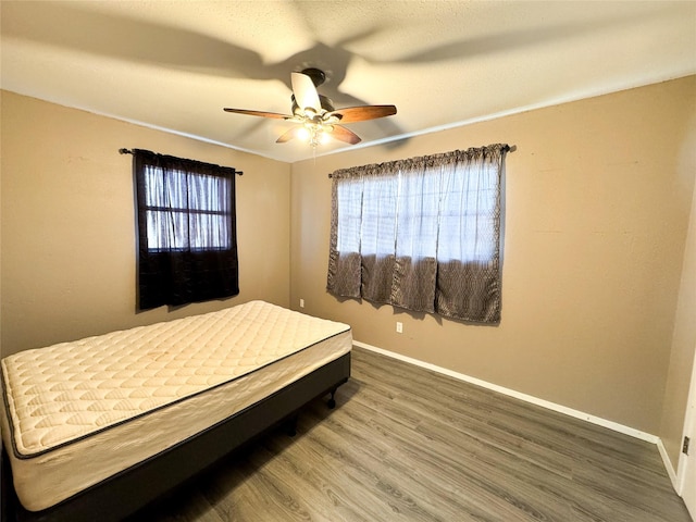 311 S Fir Ave, Munday, TX 76371 - bedroom with baseboards, ceiling fan, and wood finished floors