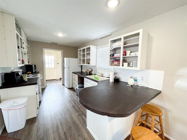 311 S Fir Ave, Munday, TX 76371 - kitchen with white appliances, dark countertops, a sink, and a peninsula