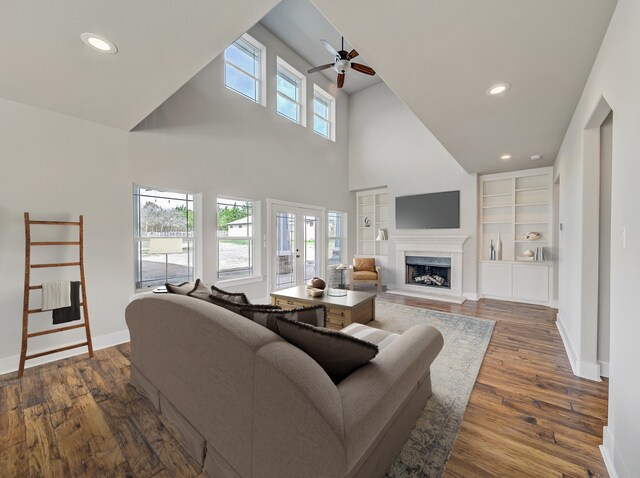 living area with a ceiling fan, a fireplace with raised hearth, baseboards, recessed lighting, and dark wood-style flooring