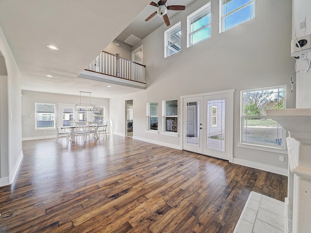 unfurnished living room with recessed lighting, ceiling fan with notable chandelier, baseboards, and wood finished floors