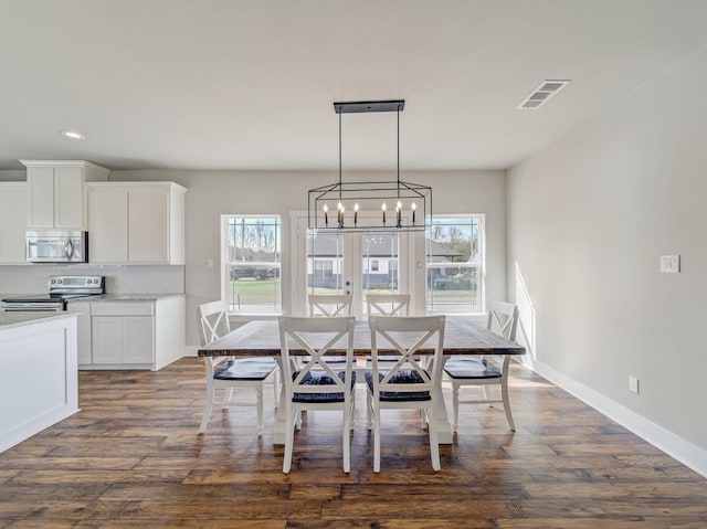 unfurnished dining area with dark wood-style flooring, a healthy amount of sunlight, a chandelier, and visible vents