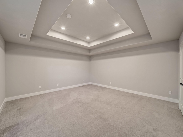 carpeted empty room featuring baseboards, visible vents, recessed lighting, and a raised ceiling